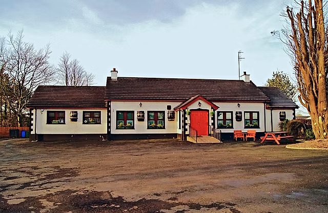 The Scenic Inn from the car park, a white single-storey building with a red door