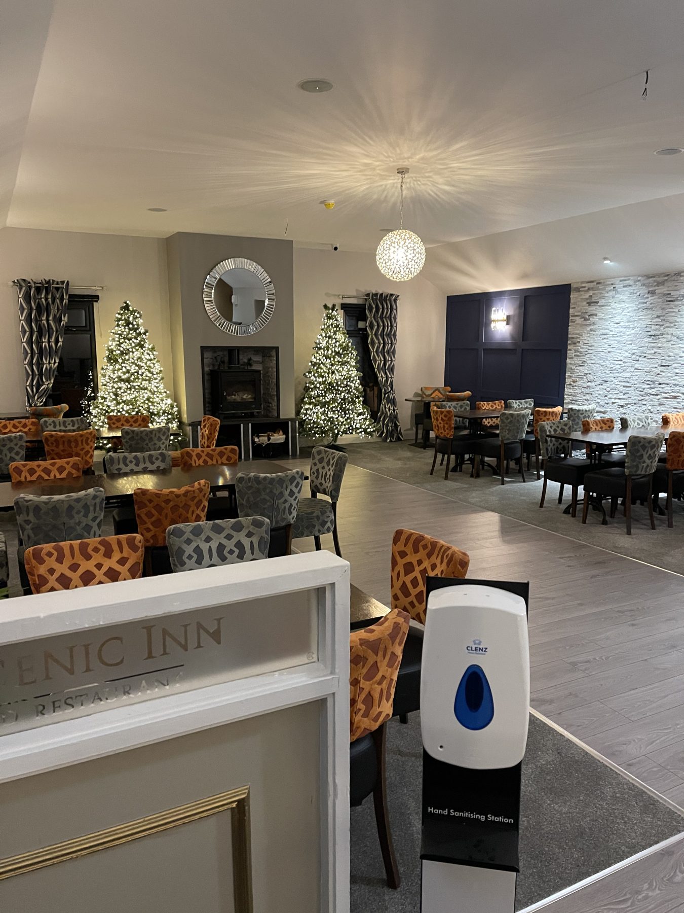 The dining room decorated for Christmas, with two trees by the fireplace